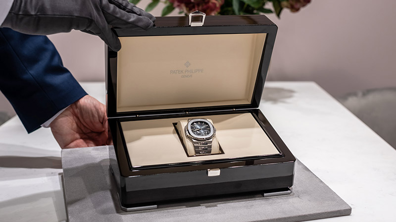 Salesperson wearing gloves presenting a Patek Philippe Nautilus 5712/1A in its box